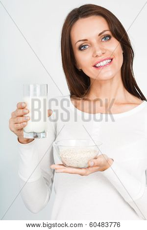 woman holding glass of mik and bowl with oatmeal