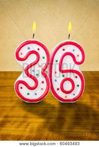 Burning birthday candles number 36 on a wooden background