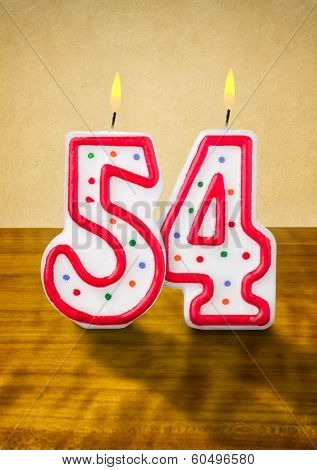 Burning birthday candles number 54 on a wooden background