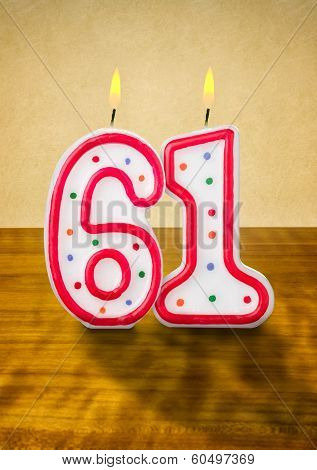 Burning birthday candles number 61 on a wooden background