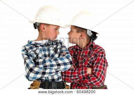 Two Young  Brothers Sneering At Each Other Wearing Construction Hardhats
