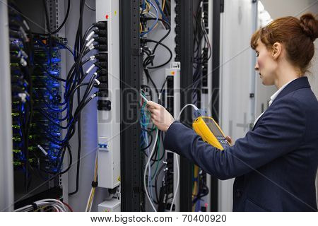 Technician using digital cable analyzer on server in large data center