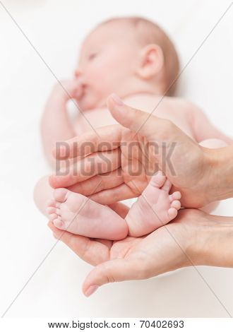 Mother Gently Hold Baby Girl Legs In Hands