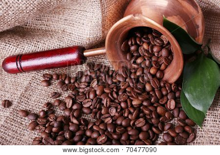 Coffee beans in ibrik on sacking background closeup