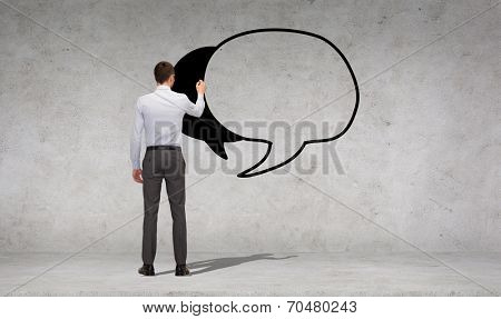 business and office people concept - businessman or teacher with marker drawing text bubble over concrete wall background from back