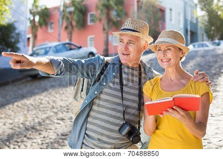 Happy tourist couple using guide book in the city on a sunny day