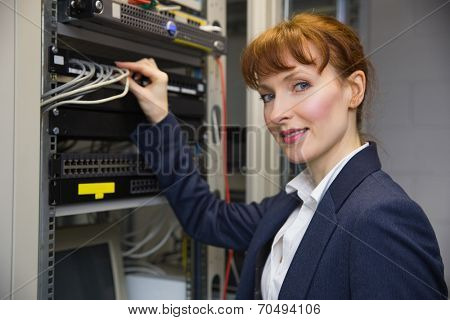 Pretty computer technician smiling at camePretty computer technician smiling at camera while fixing server in large data center