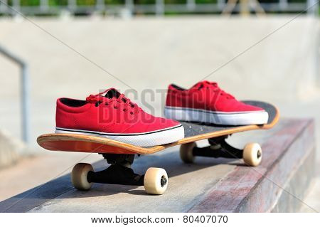 skateboard and sneakers at skatepark