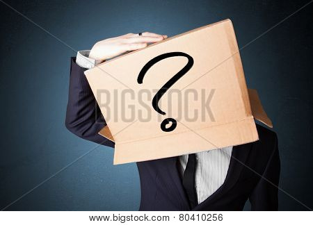 Businessman standing and gesturing with a cardboard box on his head with question mark