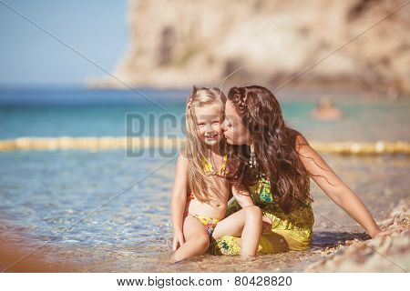 Happy mom and her adorable little daughter during summer vacation on the beach