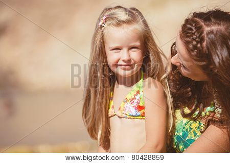 Happy mom and her adorable little daughter during summer vacation on the beach
