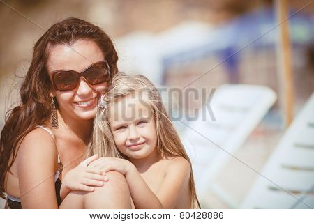Happy mom and her adorable little daughter during summer vacation on the beach