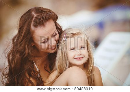 Happy mom and her adorable little daughter during summer vacation on the beach