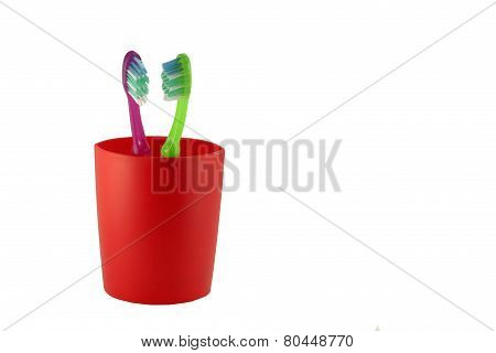 two tooth brushes in red glass