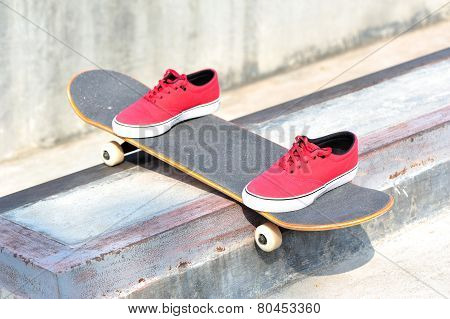 skateboard and sneakers at skatepark