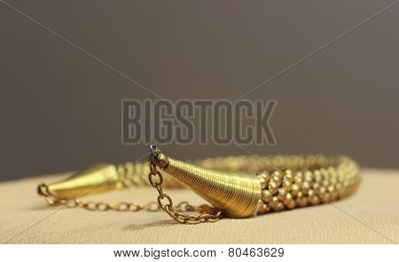 Gold jewelry kept on a beige cloth over brown background