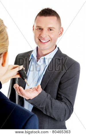 Car salesman handing over the keys for a new car to a young businessman