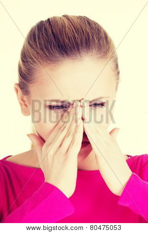 Young caucassian woman is having sinus pressure, touching her nose. 
