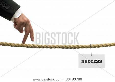 Businessman Walking His Fingers Along A Length Of Rope Or A Tightrope Towards Success