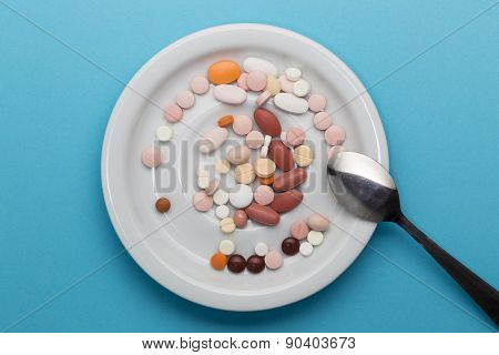 Different pills on a plate with spoon