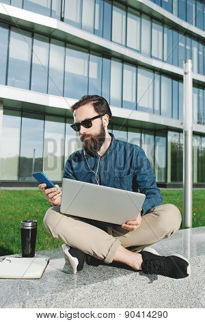 Businessman In Sunglasses With Laptop Making Call Outdoors