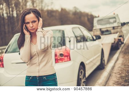 Woman calling while tow truck picking up her car