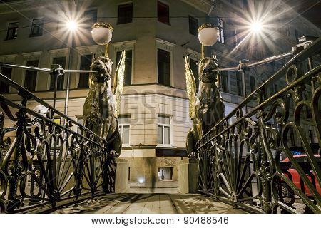 Griffins On Bank Bridge Across The Griboyedov Canal In Night Illumination In St. Petersburg