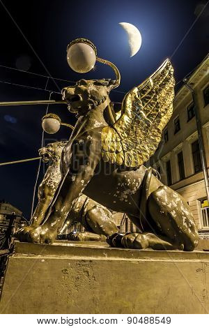 Griffins On Bank Bridge Across The Griboyedov Canal In Moonlight Night In St. Petersburg