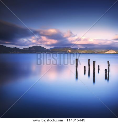 Wooden Pier Or Jetty Remains On A Blue Lake Sunset And Sky Reflection On Water. Versilia Tuscany, It
