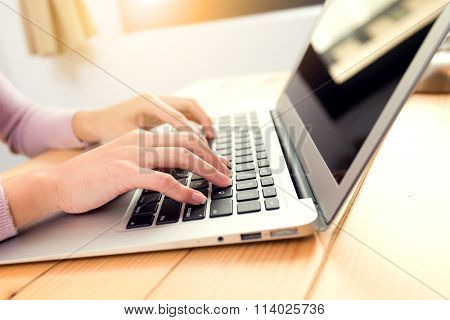 Woman typing report on notebok computer