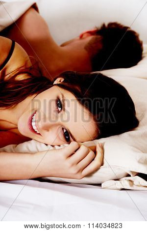 Happt woman and sleeping man in bed.