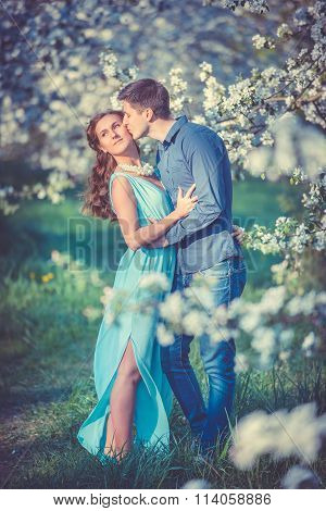 Young beautiful couple in love among apple trees