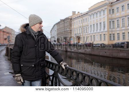 Mature man in winter clothes at the embankment of Moika river in St. Petersburg, Russia