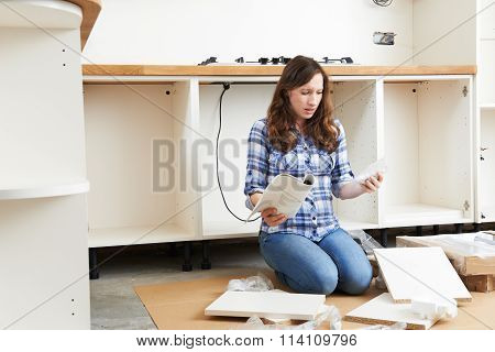 Frustrated Woman With Self Assembly Furniture In Kitchen