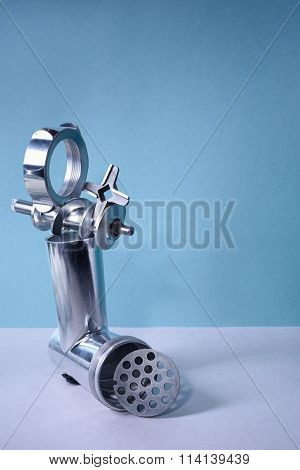 Kitchen utensil, steel meat grinder components, blue background. Free copy space.