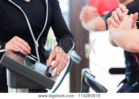 Female coach giving man and woman ems electro muscular stimulation exercise 