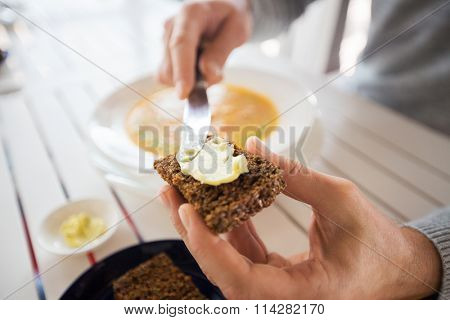 close up of hands applying butter to bread