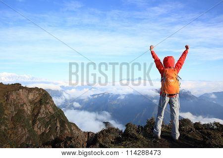 young woman backpacker hiking on mountain peak