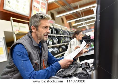 Mechanic in car shop editing invoice on computer