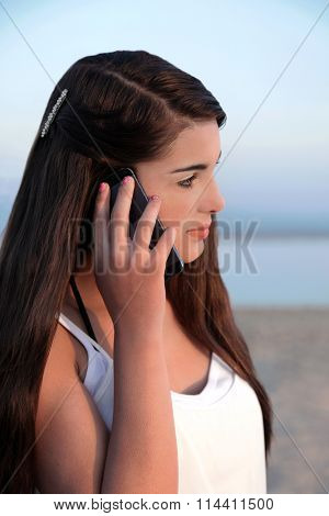 Beautiful young caucasian teenage girl with long dark hair on her cell phone.