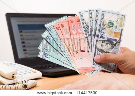 Hand Sorting Malaysia Ringgit And Us Dollar With Computer Background