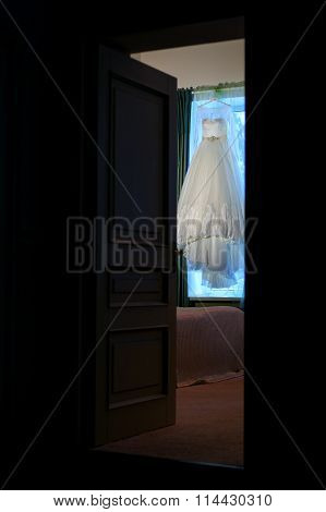 Beautiful wedding dress hanging in the doorway