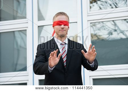 Blindfolded Businessman Standing Against Window