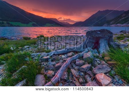 Beautiful view of the lake Resia. Dramatic sky and colorful sunset. Alps, Italy, Europe.