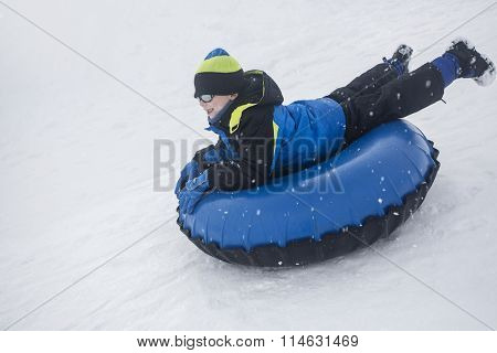 Child sledding down a hill on a snow tube on a snowy day outdoors