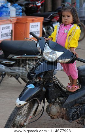 Stung Treng, Cambodia, November 25, 2012 : A Little Girl Waits On A Bike For Her Mother At The Marke