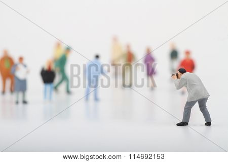 Miniature of a street photographer taking pictures of strangers walking on ta white background