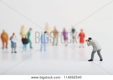 Miniature of a street photographer taking pictures of strangers walking on ta white background