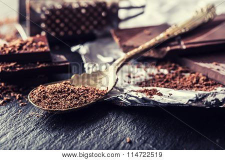 Chocolate. Black chocolate. A few cubes of black chocolate. Chocolate slabs spilled from grated choc