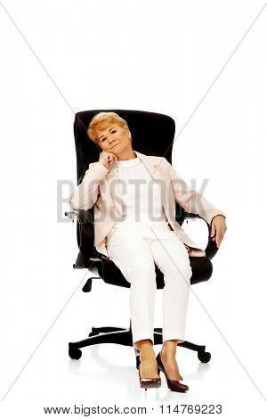 Worried elderly business woman sitting on armchair